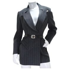 Step into the world of high fashion with our Thierry Mugler Couture 1990s Blazer, Skirt, and Belt Set. This iconic ensemble encapsulates the essence of Mugler's legendary design aesthetic, marrying structure with whimsy and commanding attention with every step. The super-structured grey pinstripe blazer is a masterpiece in itself, boasting the unmistakable Mugler silhouette. Dart detailing at the bust and shoulder pads create a powerful and confident look. Adjustable buttons at the waist ensure Mugler Clothes, Darts Fashion, Thierry Mugler Couture, Mugler Couture, Blazer Belt, Vintage Thierry Mugler, Ensemble Blazer, Pinstripe Blazer, Vintage Suits