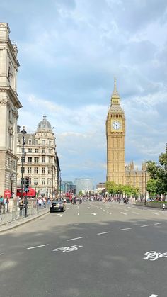 the big ben clock tower towering over the city of london as people walk down the street