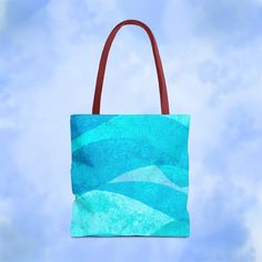 a blue tote bag hanging from a brown leather handle on a cloudy sky background