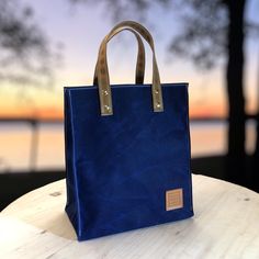 Carry the essentials of your day in this beautifully handmade tote bag. Waxed Canvas is naturally weather resistant so that your items stay safe. The feel is soft, not waxy, and dry to the touch. Made in the USA.  COLOR: Deep Water Blue ADD the optional inside pocket and secure your smaller items. DIMENSIONS: Bag: 9" wide x 5" deep x 10" tall Handles: 3/4" wide, with a 5" drop (distance from the top of the bag to the top of the handle) Optional Inside Pocket: 6.5" x 7" MORE COLORS: https://roadd Practical Rectangular Canvas Bag With Waxed Finish, Eco-friendly Everyday Waxed Canvas Bag, Practical Rectangular Waxed Canvas Bag, Practical Rectangular Bag With Waxed Finish, Rectangular Waxed Canvas Shoulder Bag With Reinforced Handles, Eco-friendly Waxed Canvas Bags For Daily Use, Rectangular Waxed Canvas Bag, Rectangular Waxed Coated Canvas Bag, Blue Waxed Canvas Bag For Daily Use