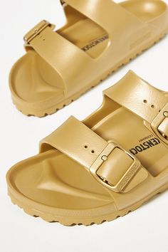 Rendered in a modern EVA finish, these sandals deliver a sporty update on the classic silhouette. You’re a shoe -in for incredible style and comfort when you slip on Birkenstock®. (P.S. it’s our favorite step when putting together an OOTD)! | Arizona EVA Sandals by Birkenstock in Gold, Women's, Size: 41 at Anthropologie Casual Gold Slides With Buckle Closure, Gold Casual Slip-on Slides, Gold Leather Footbed Slides, Gold Slides With Leather Footbed, Gold Slip-on Slides With Leather Footbed, Casual Gold Sandals With Textured Footbed, Casual Gold Synthetic Slides, Casual Gold Footbed Sandals With Removable Insole, Casual Gold Footbed Sandals For Spring