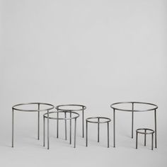 three metal tables sitting next to each other on a white surface with no one around them