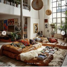 a living room filled with lots of furniture next to a tall ceiling mounted book shelf