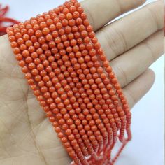 an orange beaded bracelet is being held in someone's hand with red beads on it