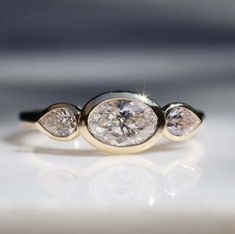 three stone diamond ring sitting on top of a white surface