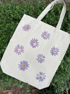 The Daisy Tote Bag is made witth real California daisies foraged in my neighborhood and hammered into canvas for the pigment to transfer. Makes a great gift! Can be done with any type of flower (if sourcing allows). Made in batches, each bag is unique, some flowers may not transfer as "perfectly" as shown here. Simple Bag Design Ideas, Tout Bag Ideas, Tote Bag Painting Ideas Flowers, Simple Tote Bag Design, Tote Bag Decoration, Canvas Bag Painting Ideas, Painted Canvas Bags, Handpainted Tote Bags, Diy Gift For Bff