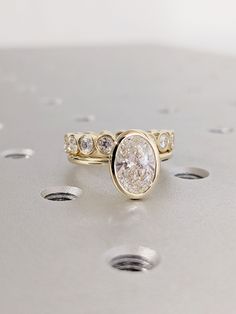 a diamond ring sitting on top of a metal surface with holes in the floor behind it