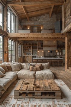 a living room filled with lots of furniture and wooden beams on the ceiling, along with large windows