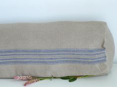 a blue and white striped pillow sitting on top of a table next to a flower