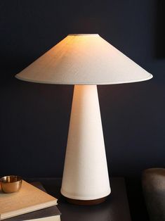 a table lamp sitting on top of a wooden table next to a book and cup