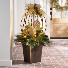 a potted plant with christmas decorations and lights on it in front of a door