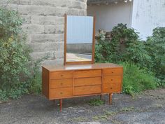 a wooden dresser sitting next to a brick wall with a mirror on top of it