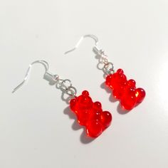 red gummy bears dangling from silver earwires on a white surface with earrings hooks