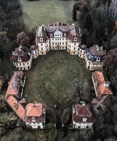 an aerial view of a large building in the middle of a field with trees around it