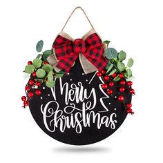 a black and red christmas ornament hanging on a wall with holly wreaths