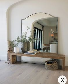 a mirror sitting on top of a wooden table next to a vase filled with flowers