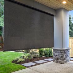 an outdoor covered patio area with stone pillars and brick columns, along with a black roller shade