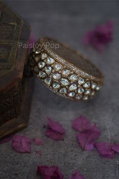 Our Victorian Polki Bangle Bracelet is one-of-a-kind, masterfully handcrafted that represents an overall mood in itself. The elegantly handcrafted uncut polkis lined with high-grade zirconia weave innumerable stories for those who wear it and those who see and adore it. The polki kada is a perfect bridal hand accessory to make your big day outshine.  Closure- Screw Sizes Available - 2.4 & 2.6 Handcrafted in Jammu and Kashmir Paisley Pop travels the depths of India to learn techniques and crafts from deep down in the local markets and villages. We give utmost importance to our quality and packaging. Our goal is to make sure you receive exactly what you are looking for and for your experience to be a special and memorable one. We are ready to help and advise you through your purchase. IT' S Heavy Fusion Style Bracelets For Celebration, Heavy Fusion Style Bracelet For Celebration, Elegant Cuff Bracelet For Rituals And Festivals, Luxury Bracelets For Festivals As Gifts, Luxury Bracelets For Festivals Gift, Handmade Kundan Bracelets For Ceremonial Occasions, Traditional Brass Cuff Bracelet For Formal Occasions, Luxury Handmade Ceremonial Bangle, Handmade Luxury Cuff Bracelet For Wedding