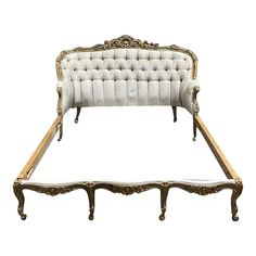 an antique style bed with gold trimmings and white upholstered headboard