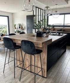 a modern kitchen with an island counter and bar stools in front of the window