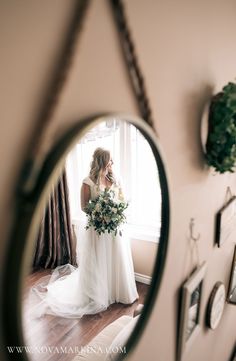 a woman standing in front of a mirror holding a bouquet