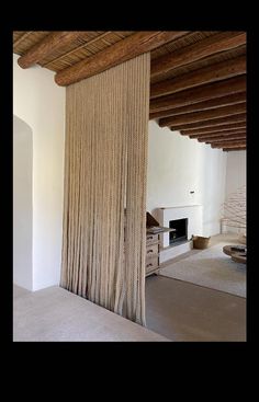 a living room with white walls and wood beams on the ceiling is decorated in natural materials