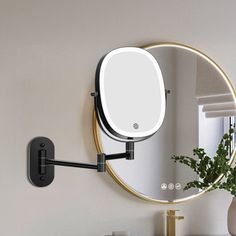 a round mirror mounted to the side of a wall next to a vase with a plant