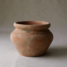 a large clay pot sitting on top of a white table next to a gray wall