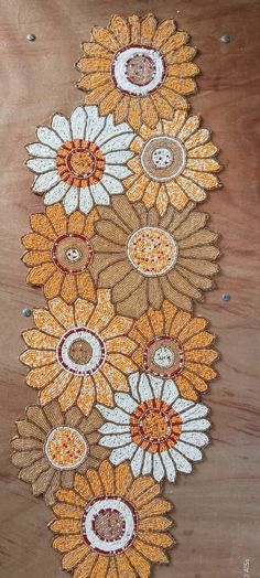 an embroidered table runner with sunflowers and circles on the edge, sitting on top of a wooden surface