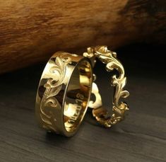 two gold wedding rings sitting on top of a wooden table