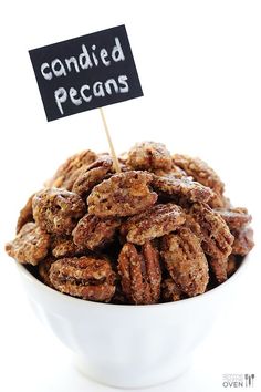 a white bowl filled with candied pecans sitting on top of a table