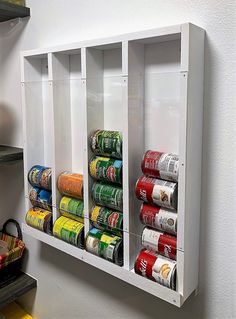 a wall mounted spice rack with cans on it and some shelves holding canned food in them