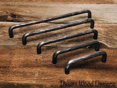 four metal handles on a wooden surface with the words desert wood designs written below them