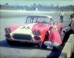 an old photo of a car being worked on by two men in front of it