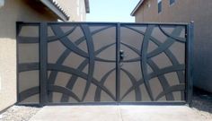 an iron gate is shown in front of a house with two doors and one door open