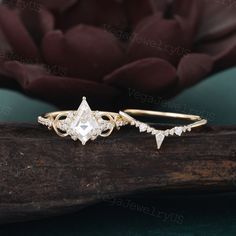 two gold rings with white diamonds on top of a piece of wood next to a flower