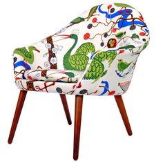 an upholstered chair with birds and flowers on the fabric, sits in front of a white background