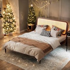 a bed sitting on top of a wooden floor next to a christmas tree in a bedroom