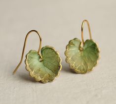 These olive green leaf earrings are brass charms with some amazing detail, which have been carefully treated, painted and varnished to bring out beautiful tones and depth of colour and to show the incredible veining and other details of the metal.  These are coloured a beautiful, delicate and multi toned olive green colour.   They are designed to be reminiscent of the beautiful, softly coloured lily pads found in Art Nouveau paintings. They are handmade in our Edinburgh studio and no two pairs are quite the same!  Our Leaf Earrings are available in two finishes: soft matte or a shiny glass appearance. The colour and level of detail on the earrings are exactly the same regardless of which you choose.  We've included an image for a better idea.   Each leaf is 15mm long. We offer these leaf e Handmade Enamel Jewelry, Green Brass Earrings Nature-inspired, Accesories Outfit Jewelry, Green Wedding Accessories, Cottagecore Accessories, Garden Earrings, Art Nouveau Earrings, Lily Earrings, Birthday Gift For Sister