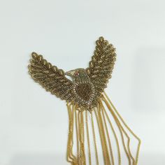 a necklace with gold chains and an owl on it's back, sitting on a white surface