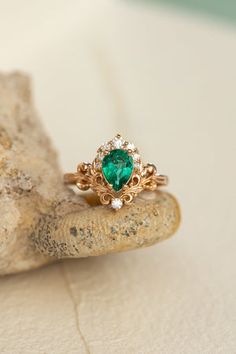 a close up of a ring with a green stone in the middle on a rock