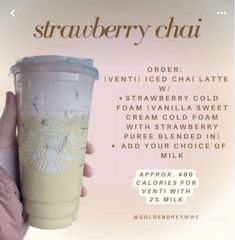 a person holding up a starbucks drink in front of a sign that says strawberry chai