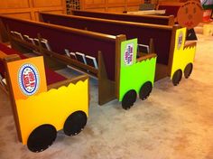 a train made out of cardboard sitting on top of a carpeted floor next to wooden benches