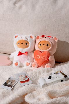 two stuffed animals sitting next to each other on a white blanket with pictures and photos