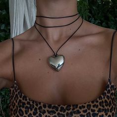 The Small Heart Necklace in Silver, also known as the viral heart necklace, features a silver heart pendant on a black cord. It can be styled and worn in various ways: tied in the front or back with a bow or a knot, wrapped around the neck or worn long, as a belt, attached to your bag, or however you choose to interpret it. The timeless design makes it a wardrobe staple and a must-have in your statement collection. The necklace is sold as one piece and comes with a logo drawstring pouch. Size: O Big Heart Necklace, Small Heart Necklace, Necklace Outfit, Heart Choker, Chunky Jewelry, Silver Heart Pendant, Silver Heart Necklace, Small Heart, Jewelry Inspo