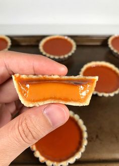 a hand holding a piece of peanut butter caramel tarts on top of a cookie sheet