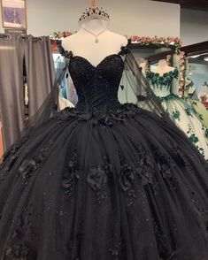 Step into your Quinceanera with elegance and mystery in this stunning black ball gown. This dress is crafted from luxurious tulle and features a dramatic ball gown silhouette with a chapel train that adds a royal finish to your look. The sweetheart neckline and long sleeves exude sophistication, while the intricate beading and appliqued floral details bring a soft yet bold charm to the ensemble. A corset back ensures a perfectly sculpted fit, making this dress as comfortable as it is enchanting. Black And Pink Quinceanera Theme, Goth Quinceanera Theme, Quinceanera Dresses With Flowers, Black Quince Theme, Black Ball Gown Dress, Long Sweet 16 Dresses, Lavender Prom Dress Long, Dresses With Flowers, Quinceanera Dresses Black