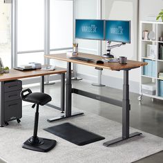 two computer monitors sitting on top of a wooden desk