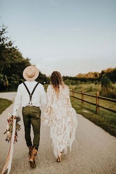 a man and woman walking down a road holding hands