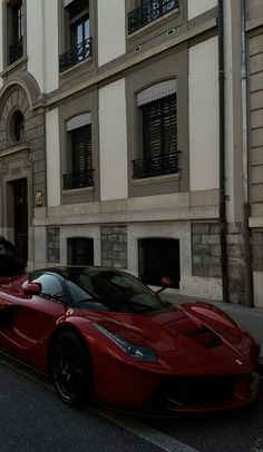 a red sports car parked on the side of a street next to a tall building